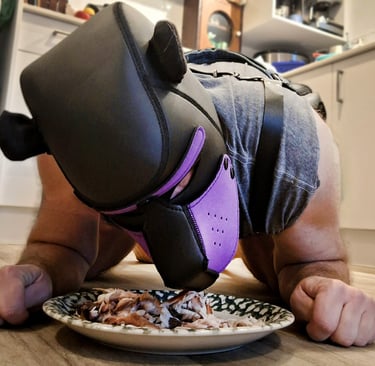 Man in a bear mask eating from a dish on the kitchen floor.