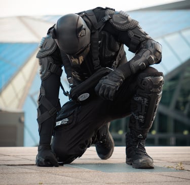 A man o his knees with his head bowed, wearing a pup mask.