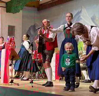 Tyrolean traditional show in Innsbruck with toddler in Christmas jumper on stage