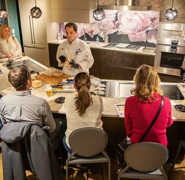Chef Andrew giving a cooking demonstration in a luxury kitchen appliance showroom.