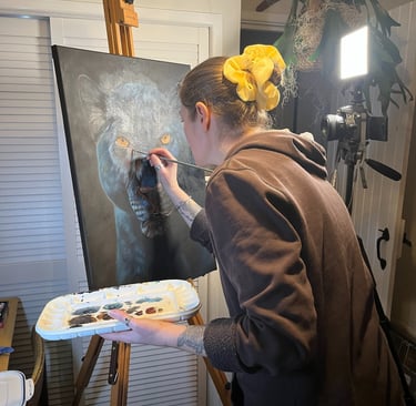 Artist painting a realistic black panther portrait on canvas with fine details.