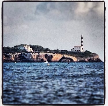 a lighthouse on a rocky island with a lighthouse in the background