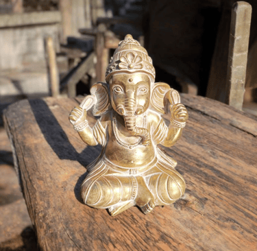 La imagen es una figura decorativa de Ganesha sobre una mesa de madera