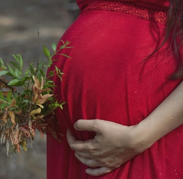 a pregnant woman in a red dress holding a bouquet