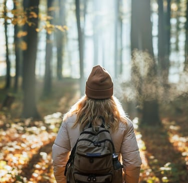 A woman in a hat and backpacker walking through a forest