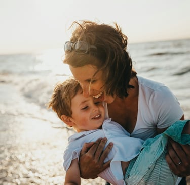 Mum and child playing at the beach laughing and enjoying life
