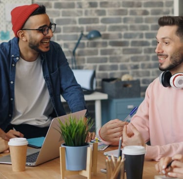 Diverse creative team collaborating and laughing during a brainstorming meeting in a modern office.