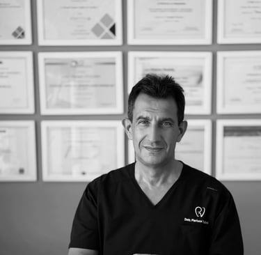 Portrait of professional dentist Dr. Pierluca Vidini in medical scrubs with dental certifications on the wall.