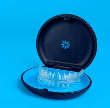 Clear teeth aligners inside a black orthodontic storage case against a bright blue background.