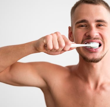 A man brushing his teeth with a white toothbrush and toothpaste for daily oral hygiene.