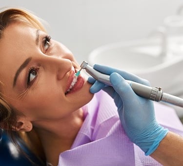A patient receives a professional dental cleaning and tooth polishing at a dentist office.