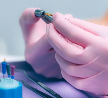 Dentist in pink gloves preparing endodontic files for a root canal procedure.