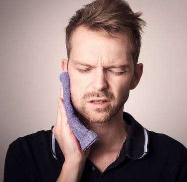 A man holding a purple washcloth to his face to relieve severe toothache and jaw pain.
