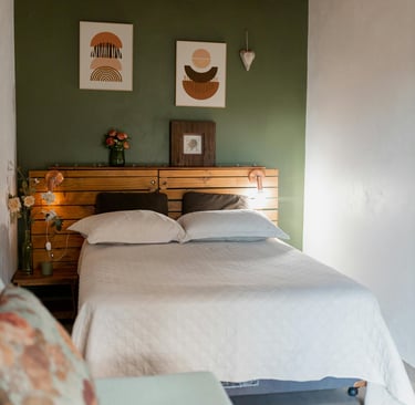 a bedroom with two beds and a wooden headboard green accent wall