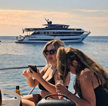chicas tomando el sol con un yate de fondo