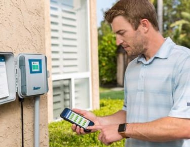 Hunter Hydrawise smart irrigation controller being adjusted with mobile app