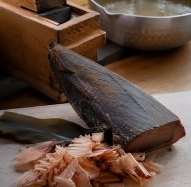 A block of dried katsuobushi with bonito flakes, kombu seaweed, and a wooden shaver for making dashi broth.