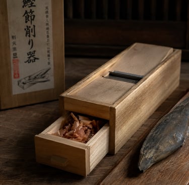 Traditional Japanese wooden katsuobushi plane with shaved bonito flakes in a drawer.