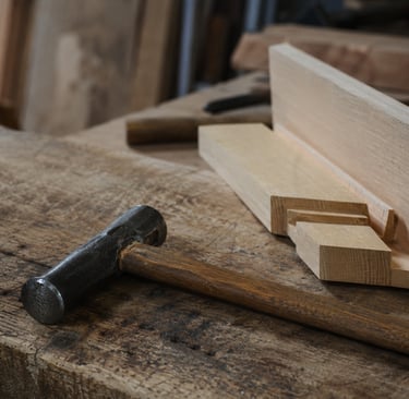 Traditional metal hammer on a rustic wooden workbench with timber joinery for carpentry projects.