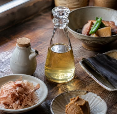 Japanese dashi ingredients including bonito flakes, miso paste, and kombu seaweed on a wooden table.