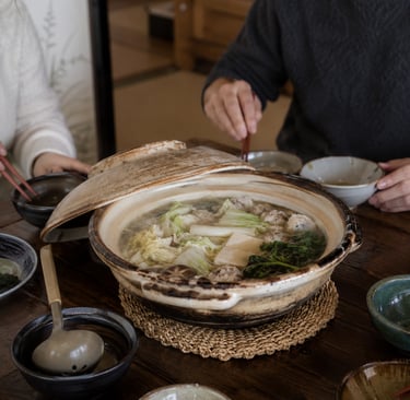 Japanese nabe hot pot with tofu and vegetables served in a ceramic donabe on a wooden table.