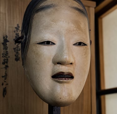 Traditional wooden Japanese Noh mask of a young woman on a display stand.