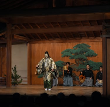 A Japanese Noh theater performance featuring a masked actor in a gold kimono and traditional musicians.