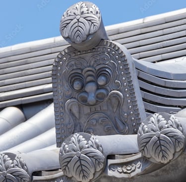 Ornate grey Oni-gawara roof tile with a carved demonic ogre face on a traditional Japanese temple.