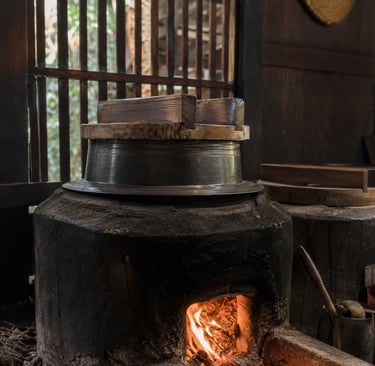 Traditional Japanese kamado clay stove with wood fire heating a hagama rice cooker pot.
