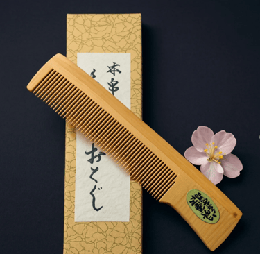 Holzkamm mit feinen Zinken, schräg auf einer dekorativen japanischen Schachtel mit Kalligrafie liege
