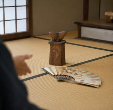 A wooden butterfly sculpture and folding fan on a traditional Japanese tatami mat floor.