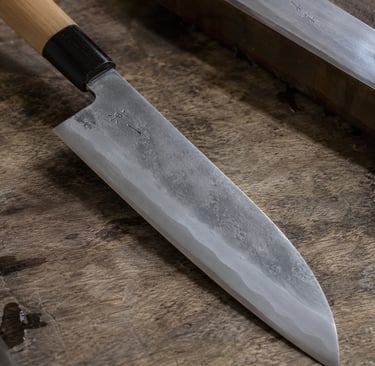A handcrafted Japanese chef knife with a high-carbon steel blade resting on a rustic wooden surface.