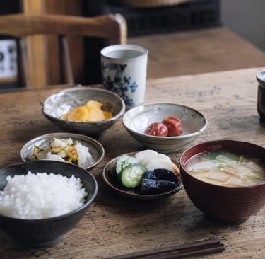 Traditional Japanese breakfast with steamed white rice, miso soup, pickled vegetables, and umeboshi.