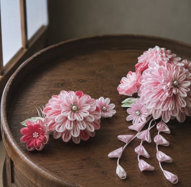 Handmade pink tsumami zaiku flower hair pins for kimono on a round wooden tray.