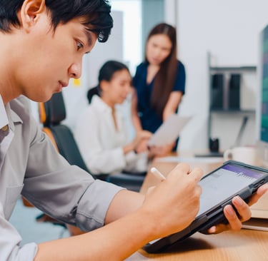 a man sitting at a table with a tablet and a woman standing next to him