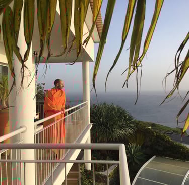 Bruno Meireles in orange robe standing on balcony of Indigo Star House