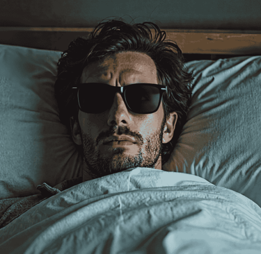 Man wearing dark shades in bed