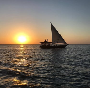 Tourists enjoying a magical sunset on a traditional dhow cruise in Zanzibar, Tanzania.