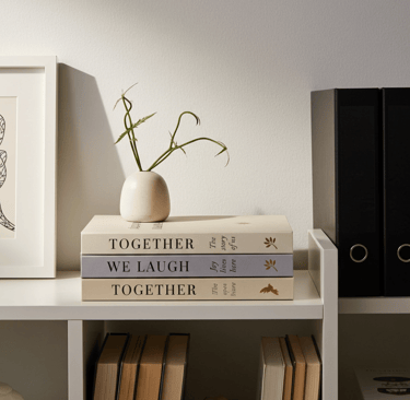 Neutral decorative book set styled on a modern white coffee table with friends enjoying coffee 