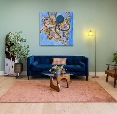 A modern, attractive waiting room with a blue velvet sofa and large art on the walls