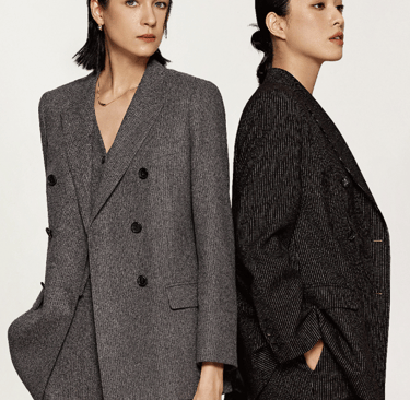 two women in suits standing next to each other