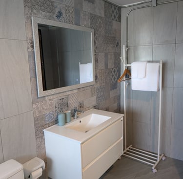 Cottage bathroom with patterned tile wall, large mirror and simple modern fittings