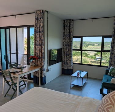 Bright cottage interior with dining table, sofa and wide windows facing the orchard