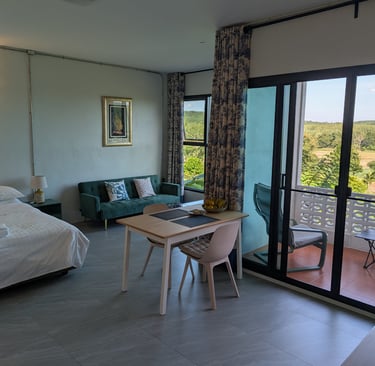 Cottage room with bed, dining area and sliding doors opening to balcony with valley views