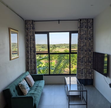 Cottage sitting area with green sofa and large window overlooking orchard and hills