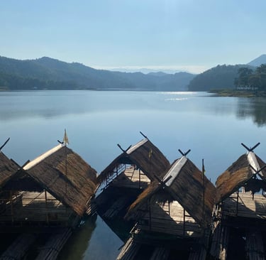 Bamboo rafts on calm water at Huai Krathing surrounded by forested hills