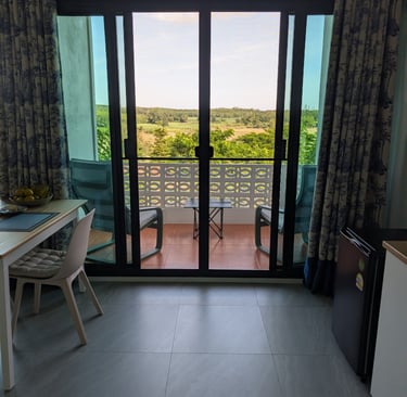 Interior view towards balcony with chairs and wide valley outlook through sliding doors