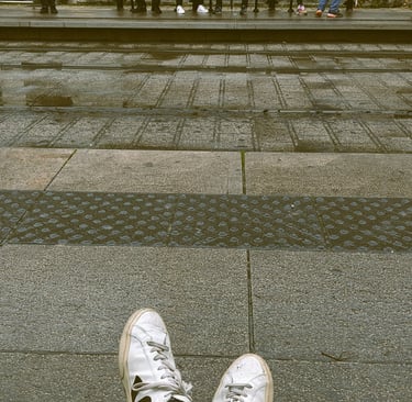 Vue de mes pieds dans mes chaussures blanches en attendant le tramway à Montpellier