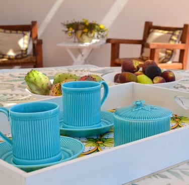 a tray with a tray of tea cups and a bowl of fruit