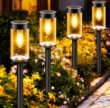 Four glowing solar garden lights illuminating a flower bed path at night with warm yellow light.